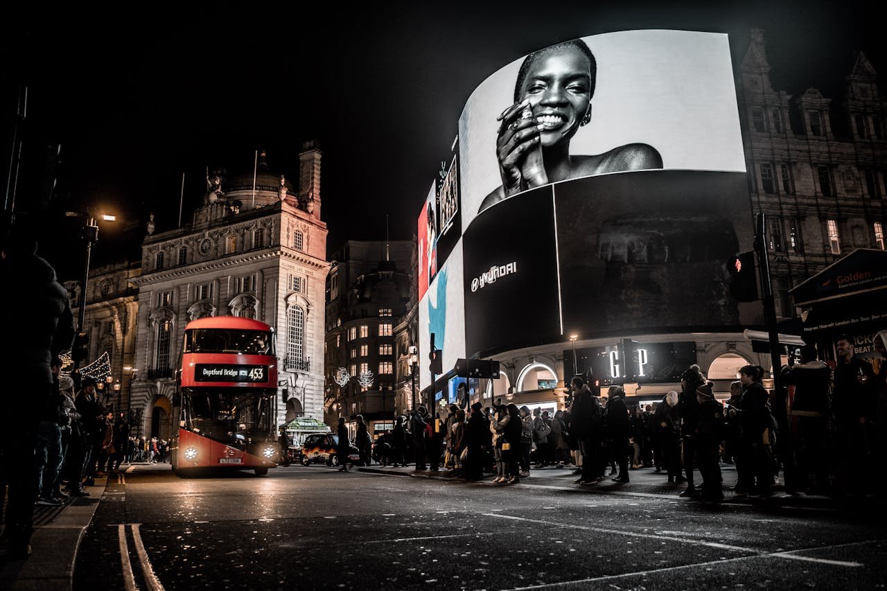 services-01 Vibrant city life at night in Piccadilly Circus, London with double-decker bus and illuminated billboards.